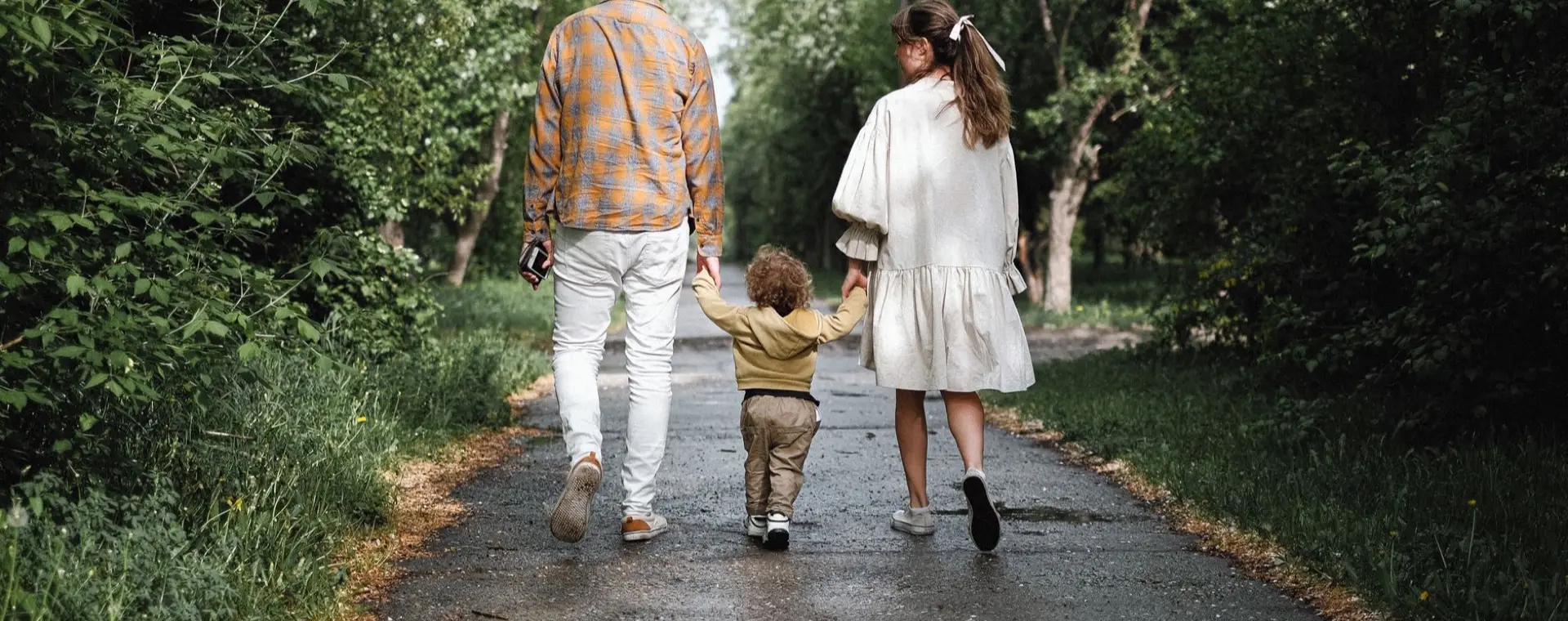 Elternteil und Kind gehen Hand in Hand einen Weg entlang
